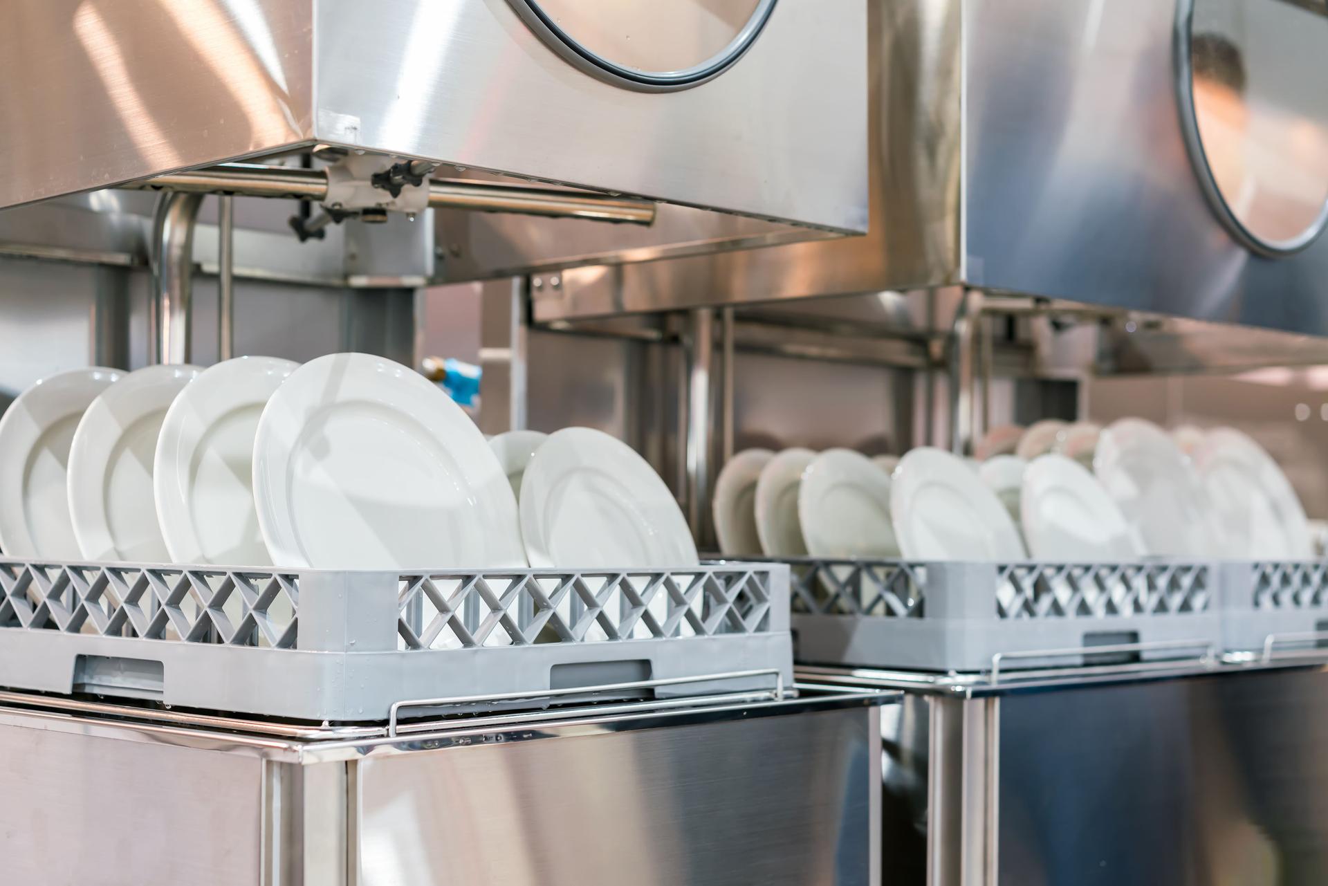 many white plate on basket in automatic dishwasher machine for restaurant industrial